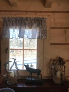 a window in a cabin with a deer statue in front of it at Dartmoor Cottage in Steninge