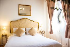 una camera da letto con un letto con lenzuola bianche e uno specchio di Hotel Casa la Tablada a Cartagena de Indias