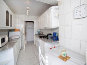 una cocina con armarios blancos y un reloj en la pared en Villa Casa Sanne by Interhome, en Calpe