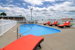 a swimming pool with red chairs on a roof at Westbridge Inn & Suites in Clinton