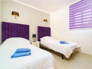 2 camas en una habitación con cortinas moradas en Apartment Pinazo by Interhome, en Cumbre del Sol
