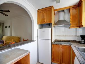 een keuken met een witte koelkast en houten kasten bij Apartment Daly by Interhome in Denia