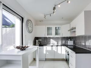 una cocina con armarios blancos y un reloj en la pared en Holiday Home Ty Castero by Interhome, en Quiberon