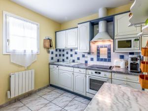 a kitchen with white cabinets and blue tiles on the wall at Holiday Home Les Grillons by Interhome in Saint-Palais-sur-Mer +14 photos