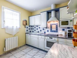 サン・パレ・シュル・メールにあるHoliday Home Les Grillons by Interhomeの白いキャビネットと青いタイルの壁が備わるキッチン