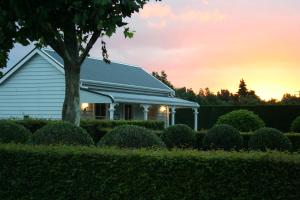 a white house with a tree and bushes at Laurella Cottage in Blenheim