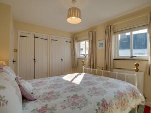1 dormitorio con 1 cama con colcha de flores en Holiday Home Spop by Interhome en Wadebridge