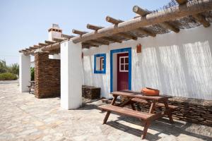 a wooden picnic table in front of a building with a blue door at Monte dos Parvos in Vila Nova de Milfontes