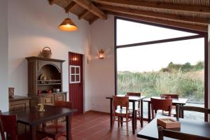 a dining room with tables and chairs and a large window at Monte dos Parvos in Vila Nova de Milfontes