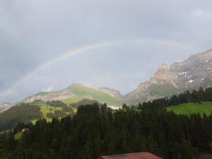 a rainbow over a valley with trees and mountains at Apartment Chalet Wäschhüsi by Interhome in Adelboden