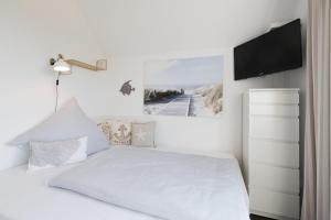 ein weißes Schlafzimmer mit einem Bett und einem Flachbild-TV in der Unterkunft Möwenblick in Olpenitz