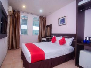 a hotel room with a large bed with red pillows at Super OYO 991 Mayfair Hotel in Kuching