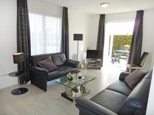 a living room with a leather couch and a table at Holiday Home de Witte Raaf-3 by Interhome in Noordwijkerhout