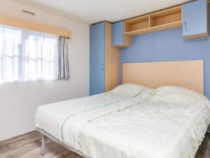 a bedroom with a bed with blue walls and a window at Holiday Home Prinsenmeer-19 by Interhome in De Beek