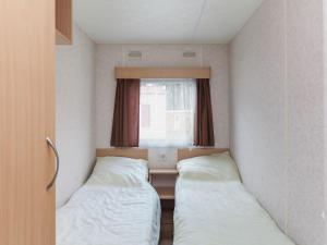 two beds in a small room with a window at Holiday Home Prinsenmeer-25 by Interhome in De Beek