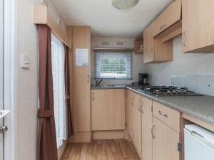 a small kitchen with wooden cabinets and a window at Holiday Home Prinsenmeer-25 by Interhome in De Beek