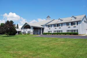 a large white building with a grass field in front of it at Cabot Inn & Suites in Lancaster