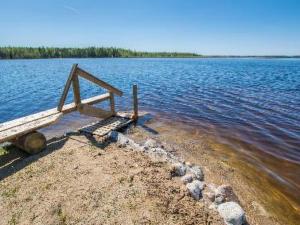 a wooden bench sitting on the shore of a lake at Holiday Home Runopuro by Interhome in Kerkonjoensuu