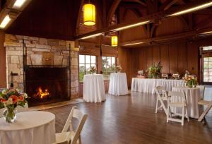 um salão de banquetes com mesas e cadeiras brancas e uma lareira em Asilomar Conference Grounds em Pacific Grove