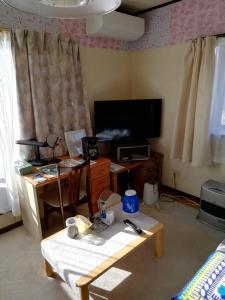 een woonkamer met een tv en een tafel en een tafel sidx sidx bij Southern Alps Kaikomagatake Foot of the Kaikoma in Hokuto