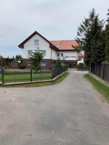 an empty road in front of a house with a fence at Willa Solna in Kołobrzeg