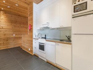 a kitchen with white appliances and wooden walls at Holiday Home Ameno 2 by Interhome in Jämsä