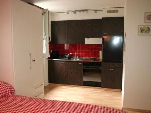 a kitchen with a black refrigerator and red tiles at Apartment Sörenweg 5 by Interhome in Engelberg