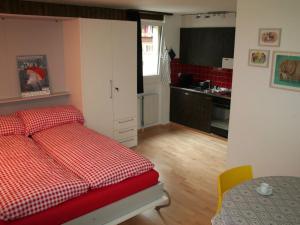 a bedroom with a red and white bed and a kitchen at Apartment Sörenweg 5 by Interhome in Engelberg