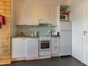 a kitchen with white appliances and wooden walls at Holiday Home Ameno 3 by Interhome in Jämsä