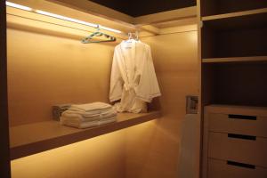 a bathroom with a robe on a shelf with towels at Guangzhou City Inn Hotel Apartment Pazhou in Guangzhou
