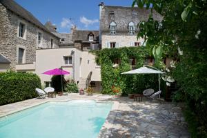 a swimming pool with chairs and umbrellas next to a building at Auberge Saint Fleuret in Estaing
