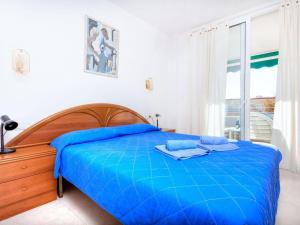 - une chambre avec un lit doté de draps bleus et une fenêtre dans l'établissement Apartment Marina Palace by Interhome, à Sant Antoni de Calonge
