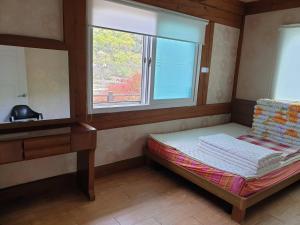 ein kleines Bett in einem Zimmer mit Fenster in der Unterkunft Tongyeong Yehyang Pension in Tongyeong