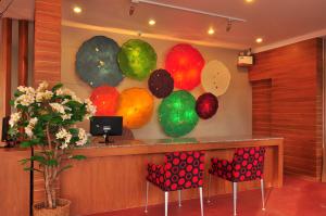 a lobby with a counter with colorful chairs in front at Phu NaNa Boutique Hotel - SHA Plus in Rawai Beach