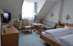 um quarto com uma cama, um sofá e uma mesa em Hotel Bayerischer Hof em Waldsassen