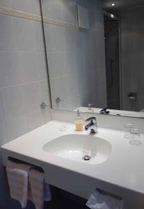 a white sink sitting under a mirror in a bathroom at Hotel Bayerischer Hof in Waldsassen