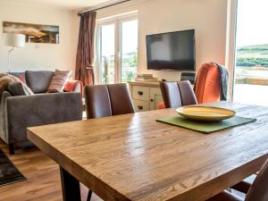 een woonkamer met een houten tafel met stoelen en een televisie bij Holiday Home Taobh na Mara by Interhome in Kensaleyre