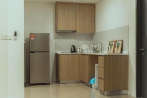 a kitchen with a stainless steel refrigerator and wooden cabinets at Muji Home 1 - Sea and City View 2BR at 218 Tropicana NEAR Komtar FoodHeaven with Netflix & TV Box in George Town