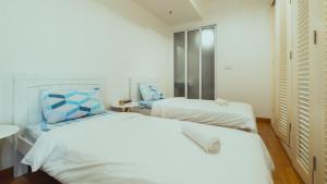 a white bedroom with two beds and a sink at Muji Home 1 - Sea and City View 2BR at 218 Tropicana NEAR Komtar FoodHeaven with Netflix & TV Box in George Town +18 photos