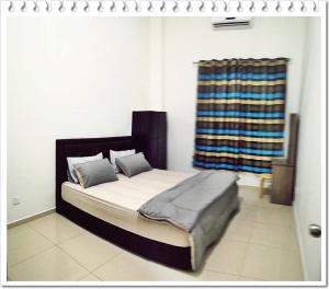 a bedroom with a bed with a blanket and a window at Fazz Homestay Melaka in Melaka