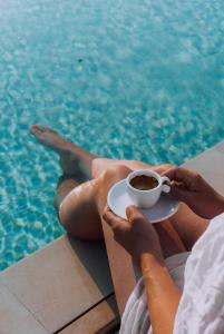 a person holding a cup of coffee next to a pool at Masseria Palane in Pat&ugrave;