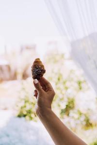 a person holding a donut in their hand at Masseria Palane in Pat&ugrave;