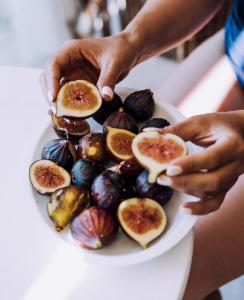 a person holding a plate of food with figs at Masseria Palane in Pat&ugrave;
