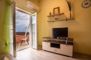- un salon avec une télévision et une porte coulissante en verre dans l'établissement Apartments Radonjić, à Kotor