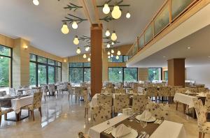 a restaurant with white tables and chairs and windows at Kackar Resort Hotel in Ayder Yaylasi