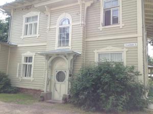 a white house with a white door and a bush at Kastani Home Accommodation in Tartu