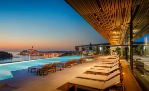 a hotel with a pool with lounge chairs and tables at Grand Park Hotel Rovinj by Maistra Collection in Rovinj