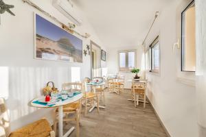 a dining room with tables and chairs and windows at B&B Rotta Per Tavolara in Porto San Paolo