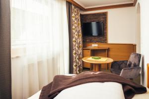 a hotel room with a bed and a table and a tv at Hotel Garni Angela in Ischgl