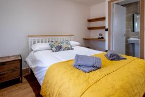 a bedroom with a large bed with a yellow blanket at Oak – Three Tuns Apartments in Pettistree
